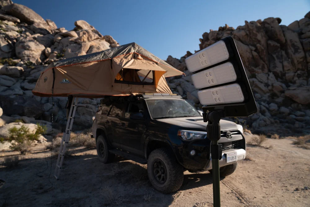 TUFF STUFF® Overland Titan 12" Solar Freestanding Light illuminating a campsite near a rugged terrain setup.