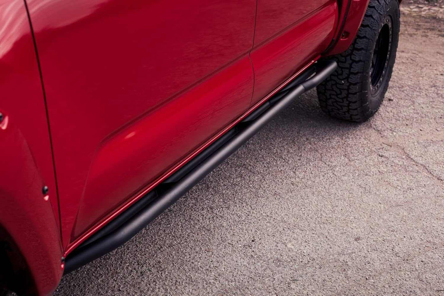 2005-2023 Toyota Tacoma Revo Rock Sliders on red truck for protection.