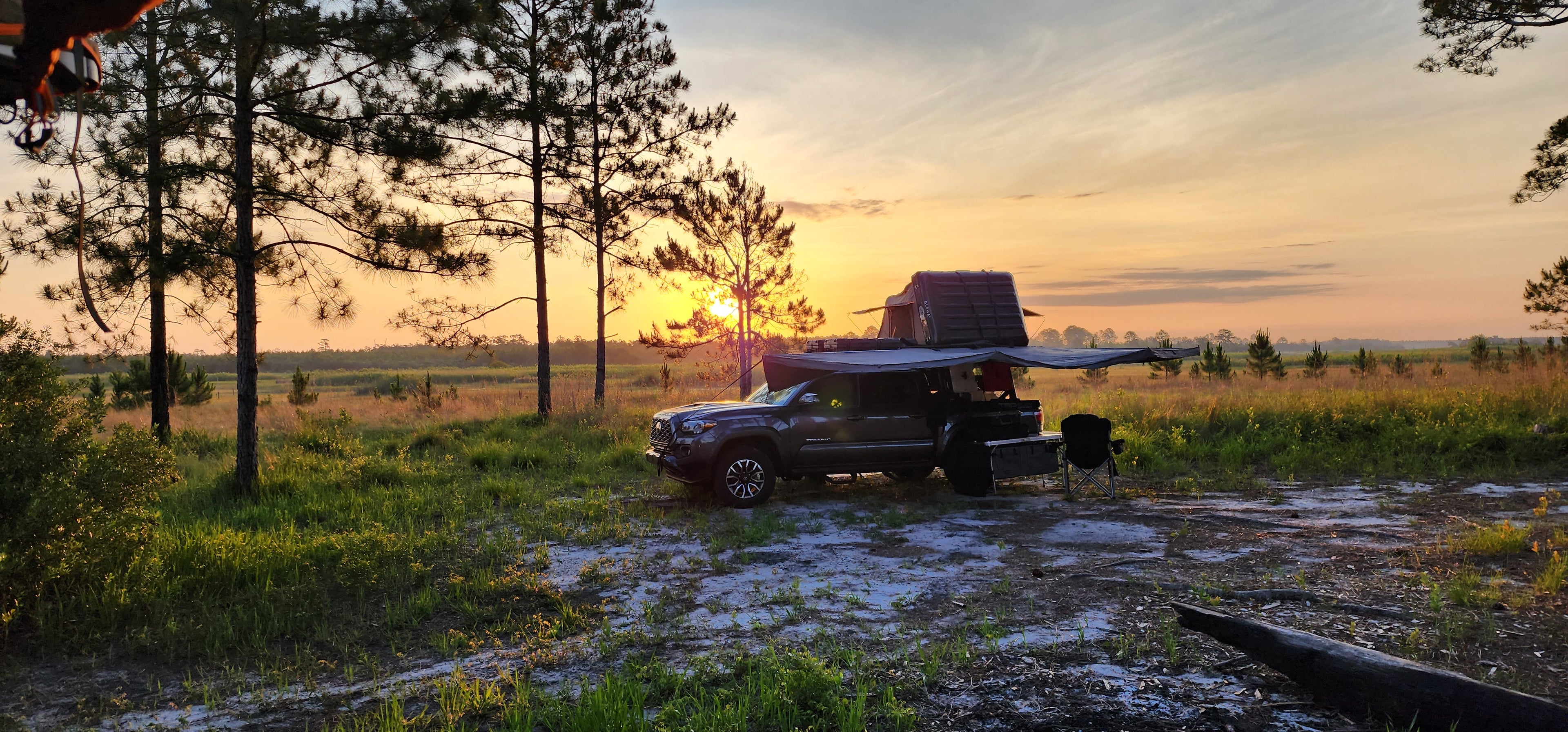 Toyota Tacoma with a roof top tent open and a scenic sunrise background