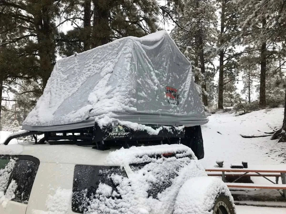 Rooftop tent covered by TUFF STUFF® Overland Xtreme Weather Cover in snowy forest.