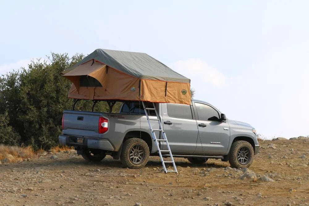 Ranger 65 rooftop tent, 3 person, tan, mounted on truck with ladder in outdoor setting.