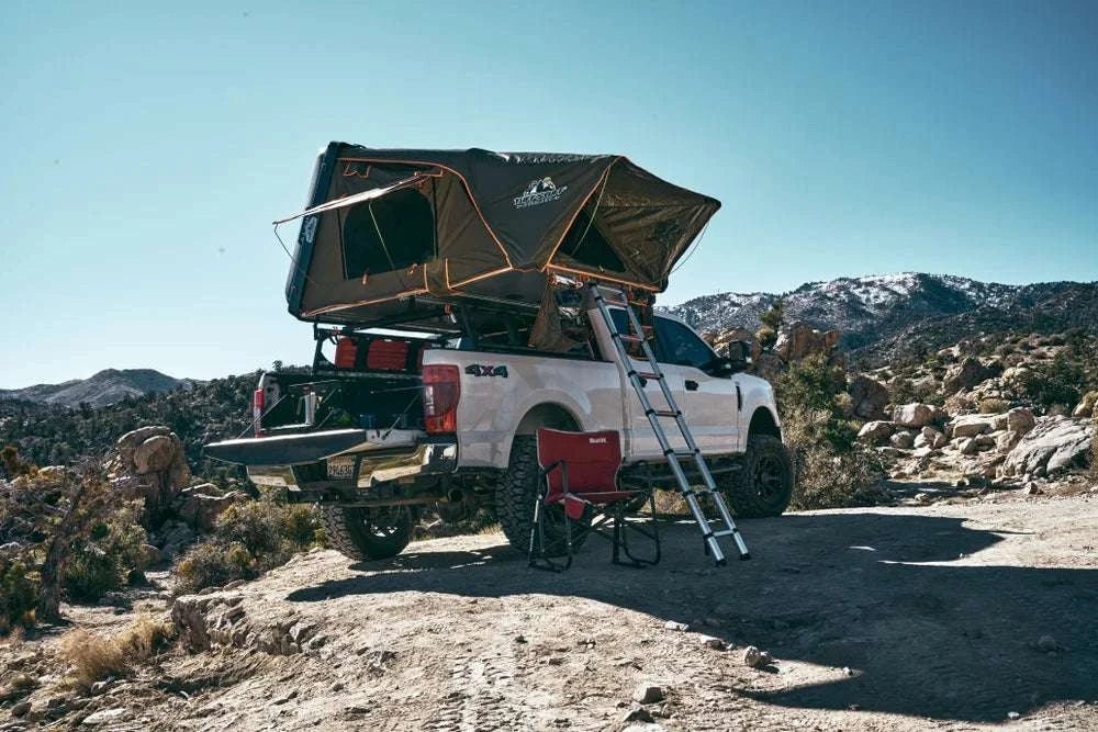 TUFF STUFF® OVERLAND ALPHA™ hard top side open tent, gray, 4 person, mounted on a truck in a rugged landscape.